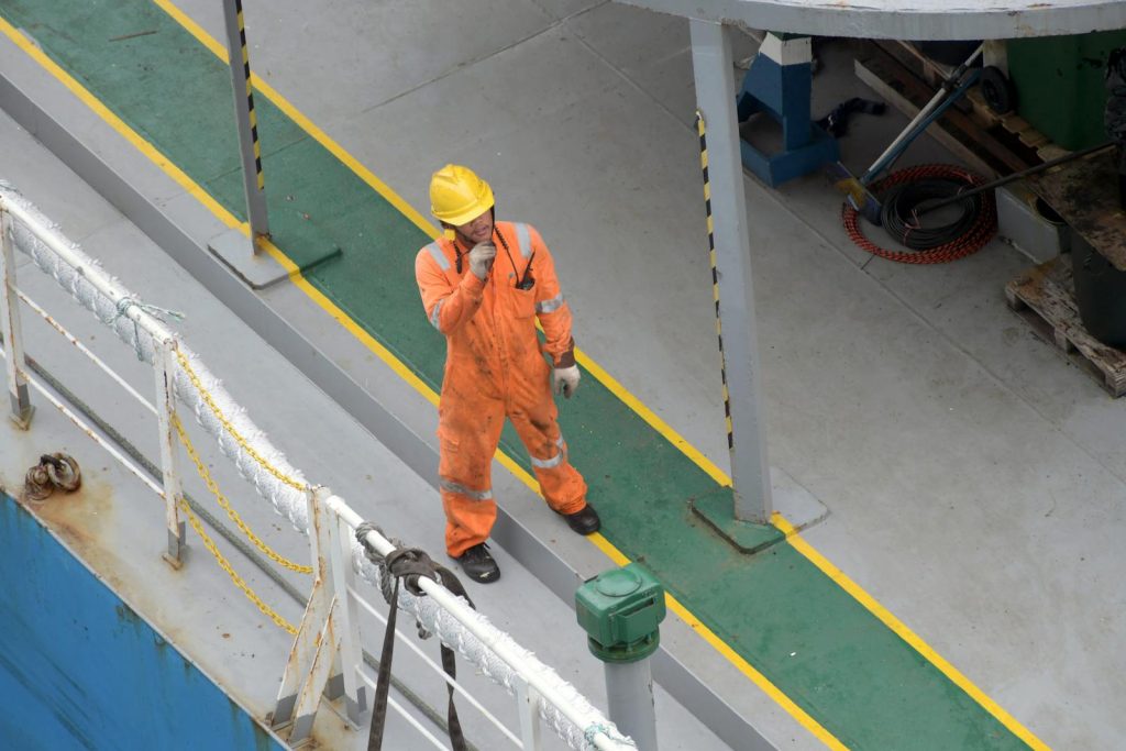 Overhead view of a worker in safety gear on a ship deck, showcasing industry standards.