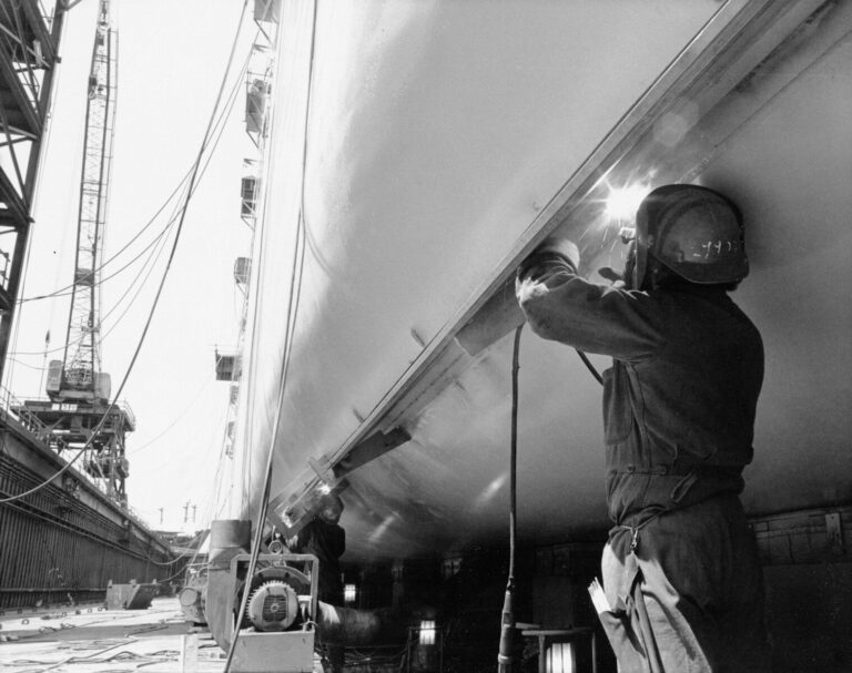 Welder working on a large ship hull in dry dock.